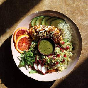 Colorful salad bowl with fresh veggies and dressing in sunlight.