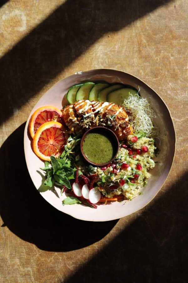 Colorful salad bowl with fresh veggies and dressing in sunlight.