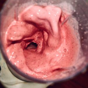 Vibrant pink smoothie blending in a high-speed blender, from above.