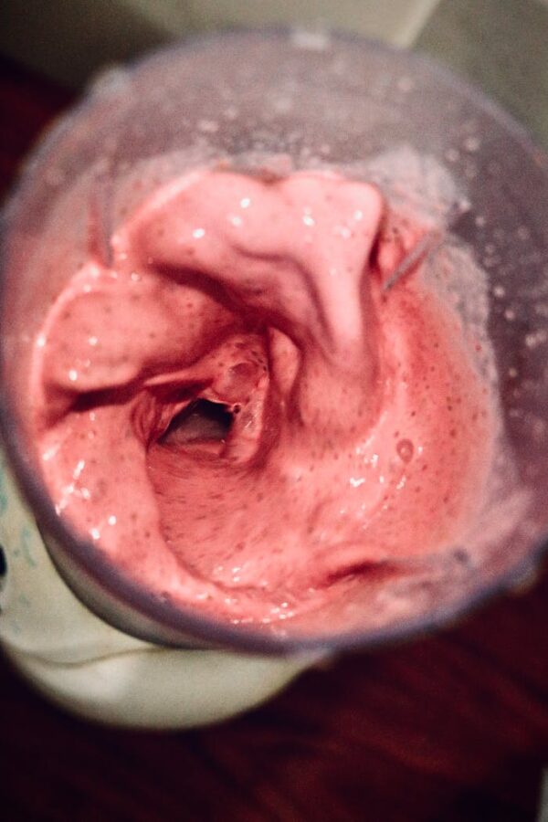 Vibrant pink smoothie blending in a high-speed blender, from above.