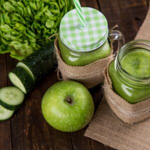 Refreshing green smoothie made with apple, cucumber, and lettuce served in mason jars on wooden background.